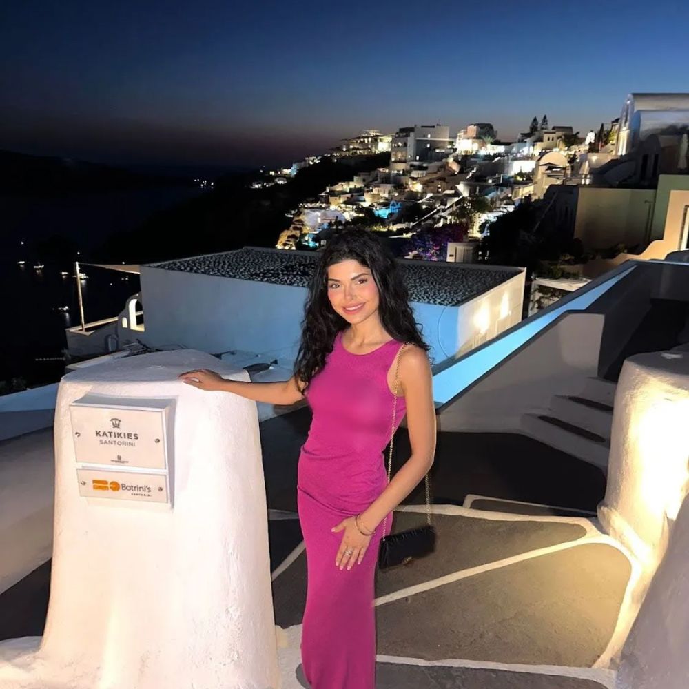 Woman in pink dress at Santorini evening setting.