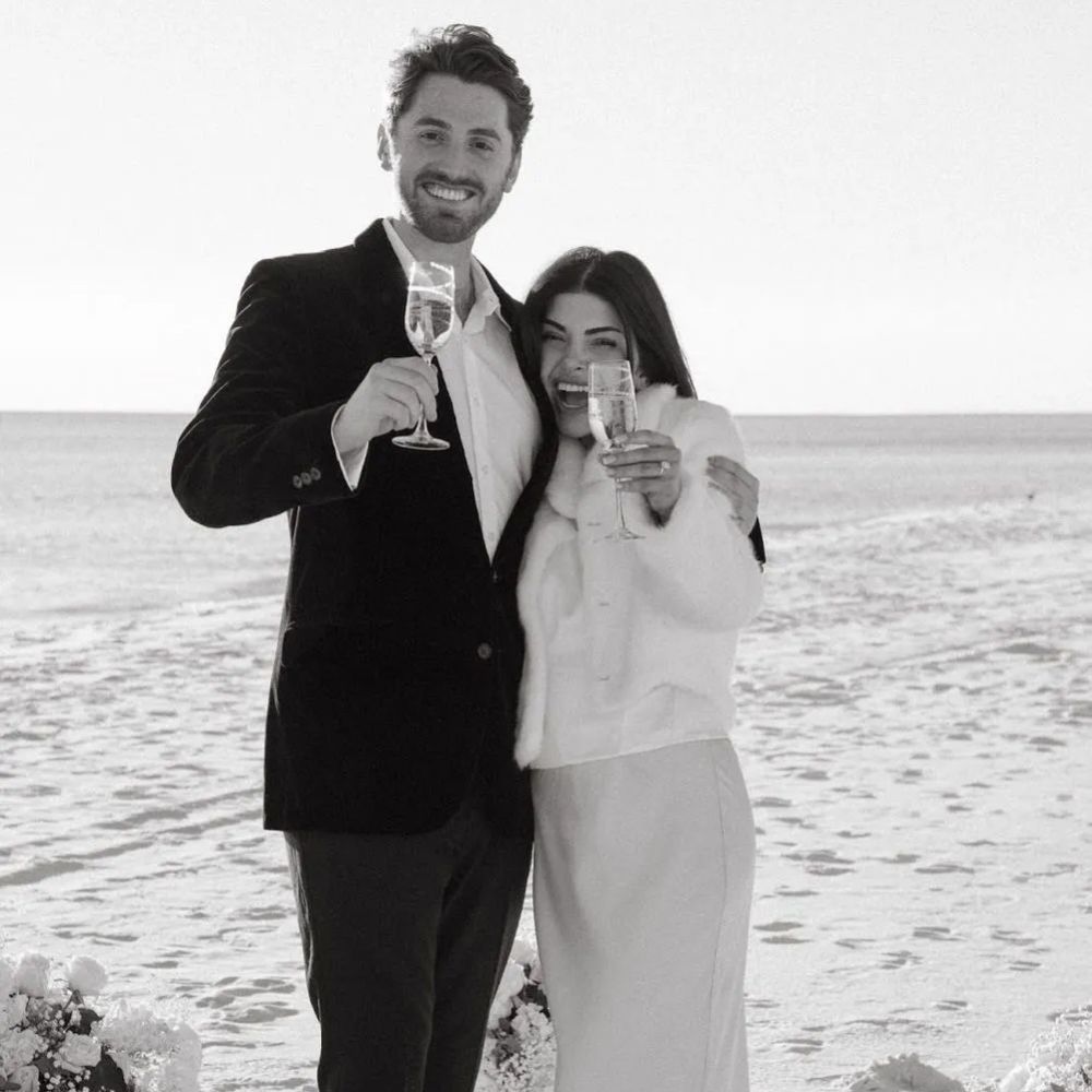 Couple celebrating on the beach with champagne.