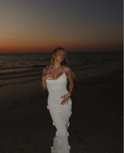 Woman in white dress by the ocean at sunset
