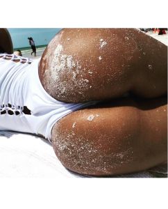 Person lounging on the beach with sandy skin.