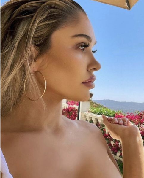 Profile of a woman with hoop earrings outdoors.