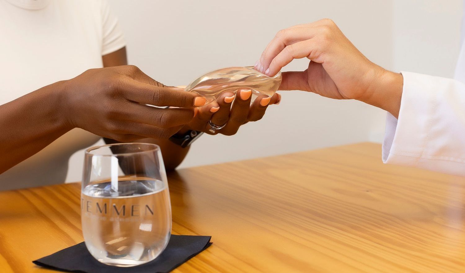 Hands exchanging a transparent silicone medical implant.